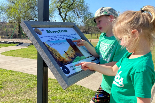 kids reading the storywalk book in fireman's park